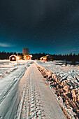 Verschneite Straße und Häuser bei Nacht