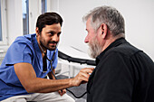 Männlicher Arzt, der einen älteren Patienten mit Stethoskop untersucht