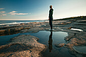 Frau an der Küste stehend und auf das Meer blickend