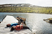 Hiking couple lying on jetty and sunbathing