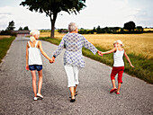 Grandma hand in hand with grandchildren in the countryside