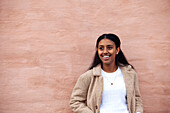 Smiling teenage girl standing against wall
