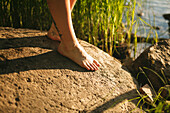 Nackter Fuß auf Felsen am Seeufer
