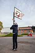Rückansicht eines jugendlichen Jungen beim Basketballspielen