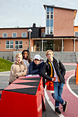 Portrait of teenage friends standing in front of school