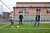 Friends playing soccer on school soccer field