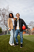 Portrait of smiling teenagers holding basketball ball