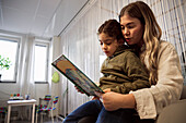 Mother and daughter reading book in waiting room