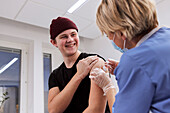 Smiling young man getting vaccinated against Covid-19