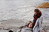 Weibliches Paar entspannt sich auf Felsen am See