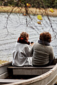 Freundinnen sitzen auf einem alten Boot am See