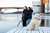 Junge Frau und Hund stehen am Fluss