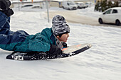 Junge beim Schlittenfahren im Winter