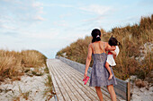 Rear view of woman carrying daughter