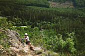 Männlicher Bergsteiger vor grüner Sommerlandschaft