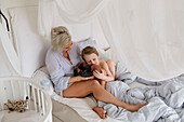 Mother and son lying in bed with newborn baby