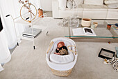 Neugeborenes Baby schlafend im Kinderbett im Wohnzimmer