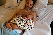 Father lying in bed with newborn child
