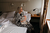 Frau im Bett sitzend mit neugeborenem Kind