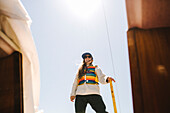 Smiling woman standing against blue sky