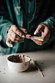 Hands of female potter holding tool