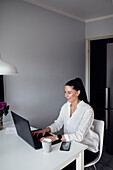 Woman in kitchen using laptop