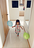 Girl walking with balloons at home