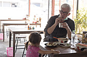 Grandfather and granddaughter eating lunch in restaurant