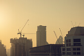 Cityscape with skyscrapers and construction cranes at sunrise