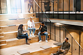 Geschäftsleute sitzen auf einer Treppe im Büro und arbeiten