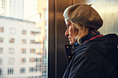 Ältere Frau schaut durch ein Fenster