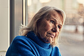 Ältere Frau schaut durch ein Fenster