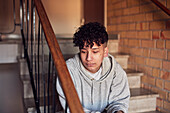 Junge sitzt auf einer Treppe in einem Wohngebäude