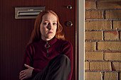 Portrait of young redhead woman sitting on stairs