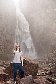 Mann macht Selfie vor einem Wasserfall