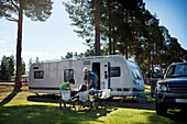 Family having meal in front of camper trailer