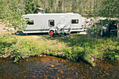 Family relaxing in front of camper trailer