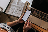 Ältere Frau bezahlt Rechnungen mit ihrem Smartphone