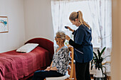 Home caretaker doing senior woman's hair