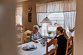 Großmutter und erwachsene Enkelin beim Essen zu Hause
