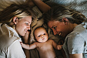 Smiling mothers lying in bed with newborn baby