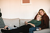 Smiling mothers relaxing on sofa with newborn baby