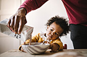 Girl watching father pour milk into bowl