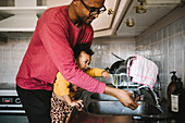 Father and daughter washing hands in kitchen sink