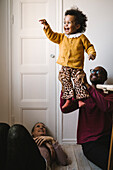 Father lifting smiling daughter at home