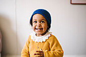 Smiling girl in yellow sweater and blue knit hat