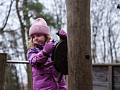 Mädchen in rosa Winterkleidung hält das Ruder auf dem Spielplatz