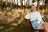 Smiling woman on bench talking via phone