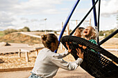Glückliche Mutter schaukelt Kinder auf dem Spielplatz