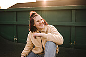 Smiling teenage girl sitting on skateboard